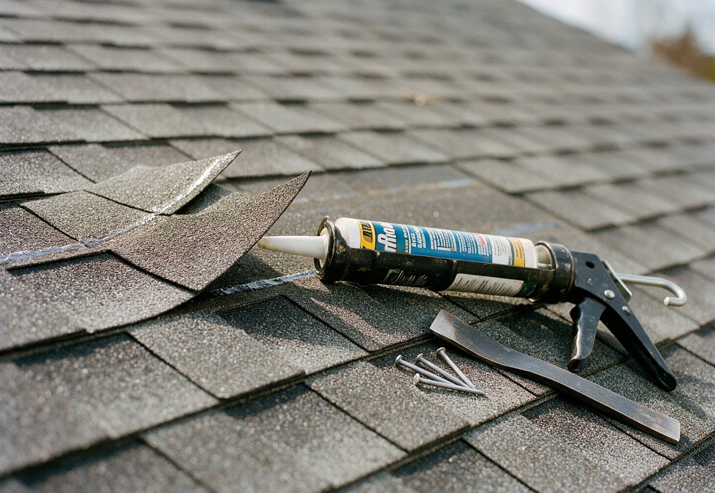 Wind-lifted shingle tabs being resealed with roofing sealant