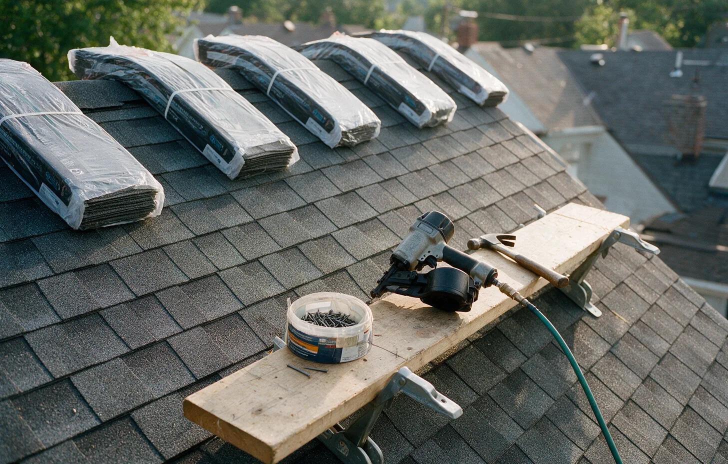 Bundles of new shingles and a roofing nailer staged on a roof